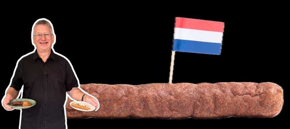 Jop met twee bordjes frikandellen naast een reuzenfrikandel met Nederlandse vlag